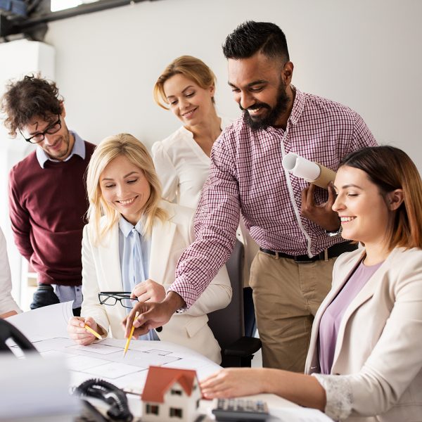 building, construction, architecture, real estate and people concept - business team with blueprint meeting and discussing house project at office
