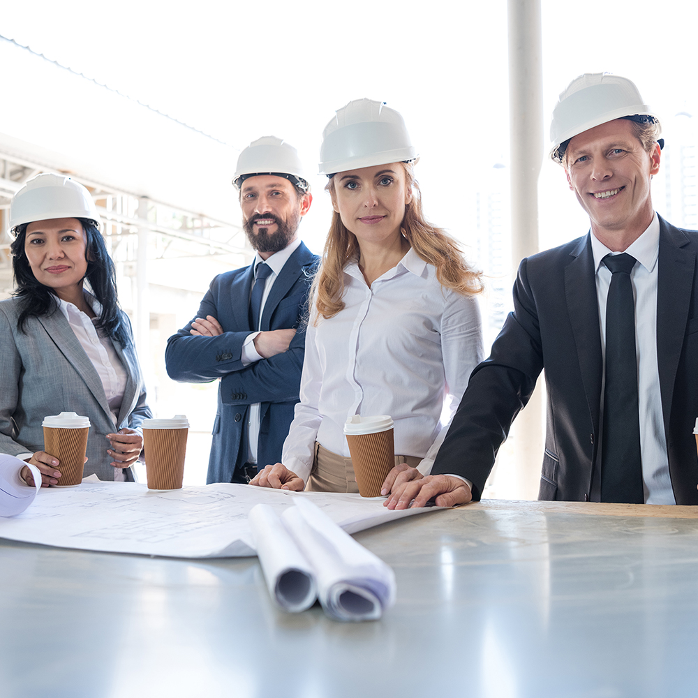 team of multiethnic contractors in formal wear working with blueprints at construction area